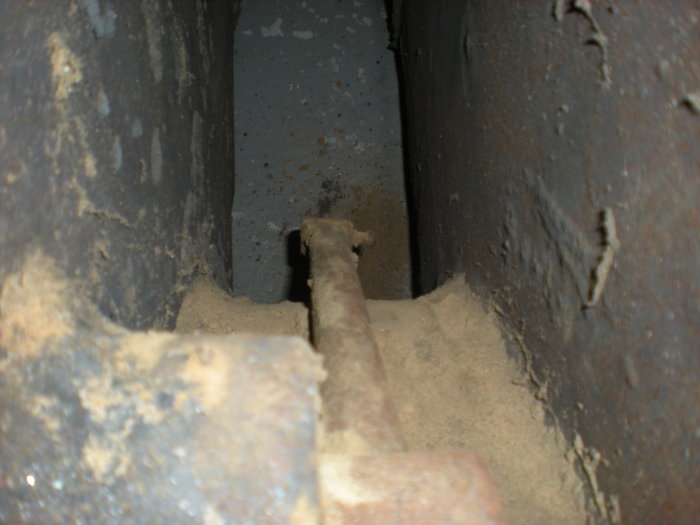 Närbild av ett omvänt stag i maskineri med rost och slitage, synligt innanför en stor metallbussning.