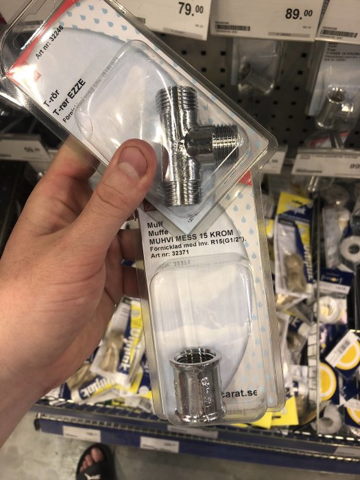 Hand håller förpackning med 1/2 tums rörkopplingsmuff i butik.
