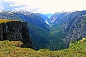 Vy över Simadalen i Norge med gröna sluttningar och en fjord i bakgrunden.