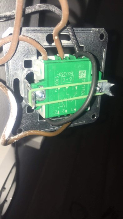 Närbild av elinstallation med öppen dubbeltrappströmbrytare och elledningar i vägg.