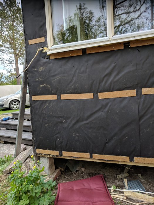 Renoveringsprojekt av en farstuutbyggnad med synlig takfot, väderskyddande duk och två justerbara plintar.