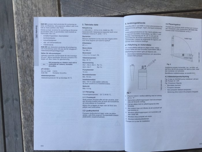 Öppen handbok med teknisk data och diagram över pumpinstallation på en träyta.