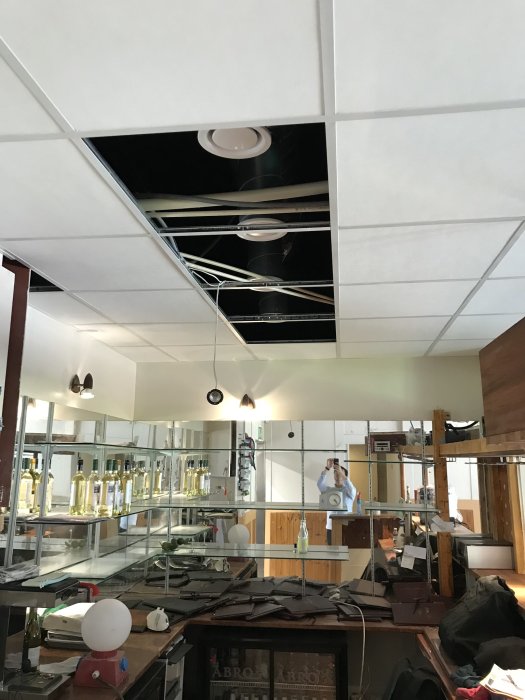 Tak med borttaget undertak som exponerar kanaler, kablar och installationer ovanför.