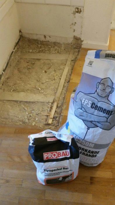 Orenat byggunderlag med träplankor och två säckar byggmaterial, Probau och EPS Cement.