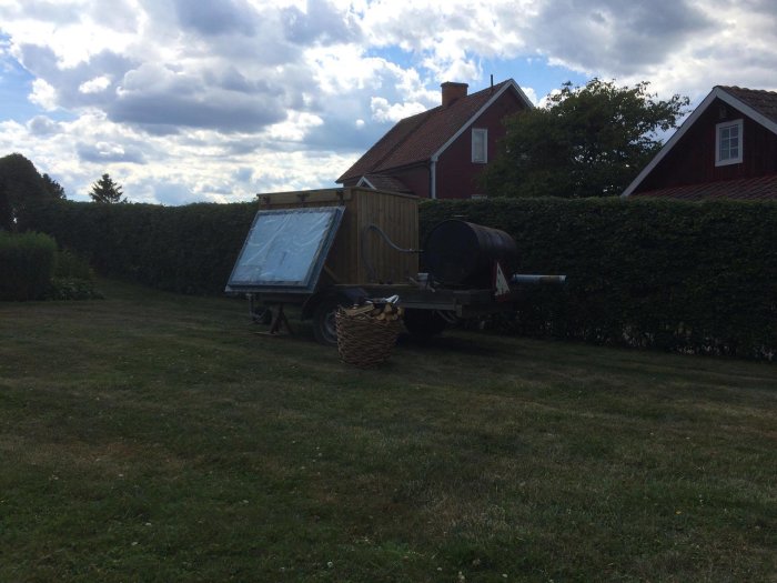 Badtunna byggd av IBC-tank monterad på släpkärra med isolering och vedeldad uppvärmning i trädgård.