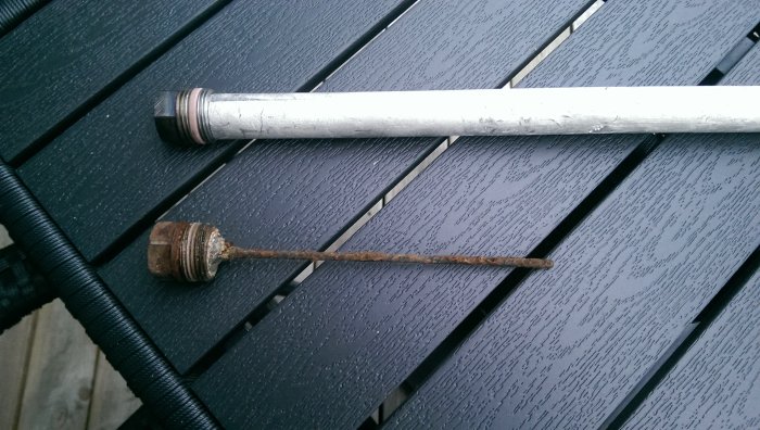 Ny anod och använd ledhandtag placerade på ett svart trägolv utomhus.