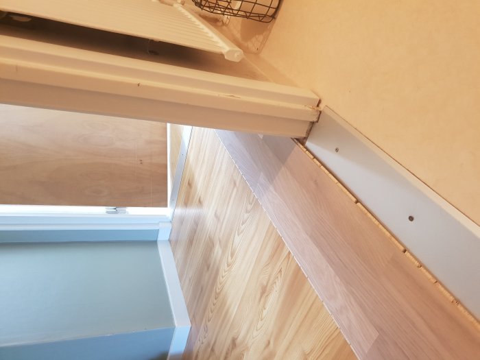 Tröskeln mellan parkettgolv och våtrumsmatta, synlig höjdskillnad.