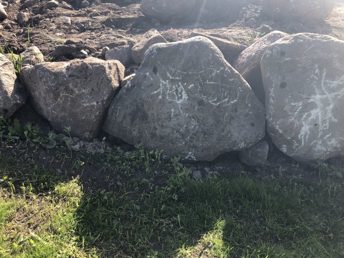 Stora stenar står på ändan i en kallmurad stödmur utan dränering vid en tomtgräns.