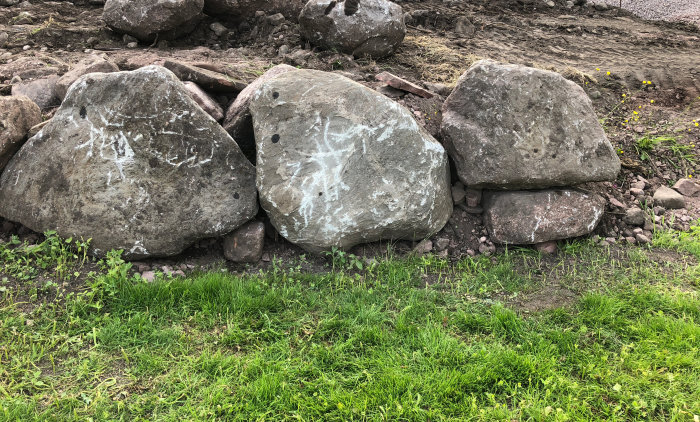 Kallmurad stödmur under konstruktion med stora stenar ovanpå gruskulle, utan dränering.