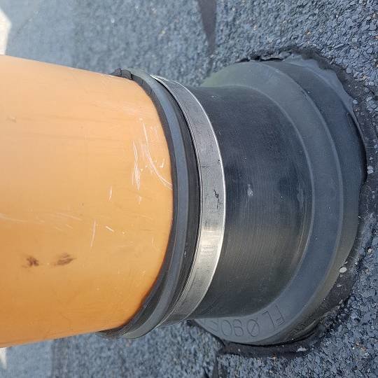 Närbild på en oanvänd avloppsventilationsgenomföring på ett tak, tätad kring rören.