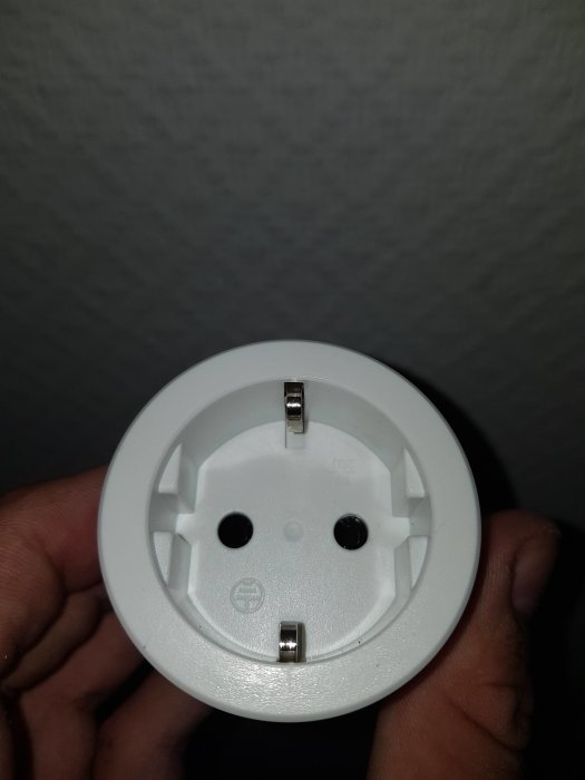 Någons hand som håller en Nexa WMR-1000 strömbrytare för smart hemkontroll utan synlig kablage.