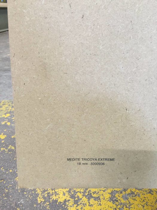 18 mm tjock MDF-skiva Medite Tricoya Extreme på ett gult fläckigt underlag.