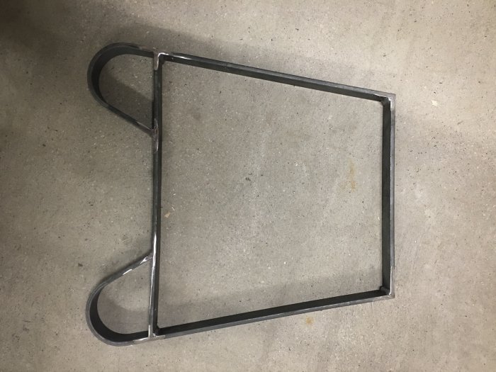 Hantillverkat metalben till bänk med elegant böjd design på betonggolv.