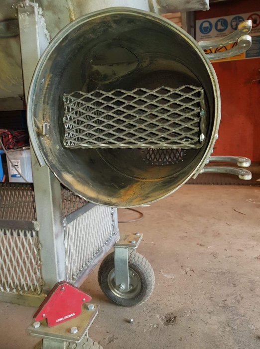 Bild av en öppen betongblandare med synlig blandningstrumma och blandararm inside.