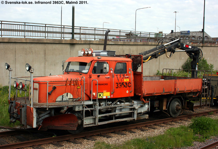 Orange arbetsfordon på järnvägsspår med kranarm och "Infranord" text, fotograferad i Malmö 2011.