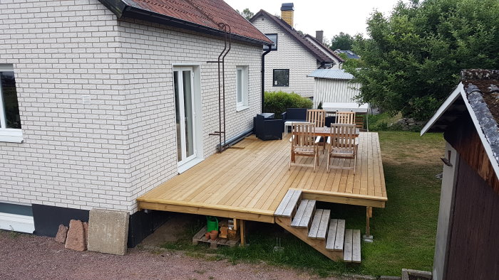 Hus med vit mexi-tegelfasad och en nybyggd terrass, där markis ska installeras över höger fönster.