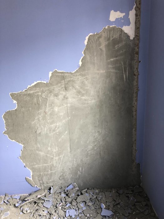 Betongvägg med delvis avlägsnad tapet och puts, exponerat område för elinstallation.