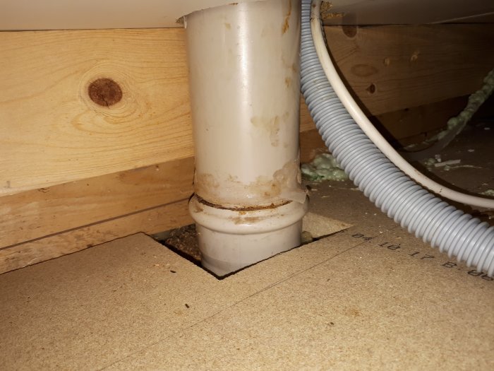 Avloppsrör går genom ett hål i köksgolvet, behov av tätning för att förhindra vattenläckage.