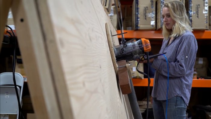 Kvinna använder en Maslow CNC-maskin på en plywoodskiva i en verkstad.