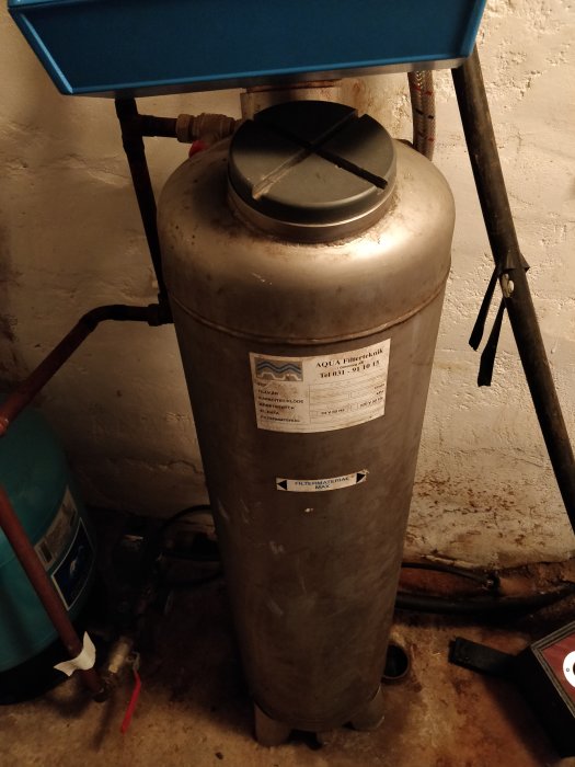 Ett gammalt vattenfilter i metall i ett hus, med märkning som är delvis svårläst, modell möjligen NA-4C.
