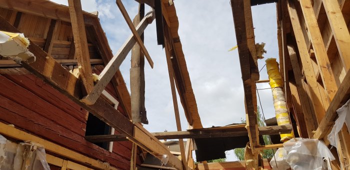 Renoveringsprojekt med borttagen råspont, exponerad stomme och tillfälliga stöttor på ett hus.