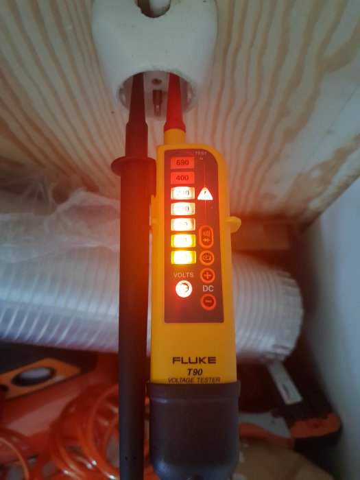 Spänningsprovare av märket Fluke T90 används för att testa eluttag med lysande varningsindikator.