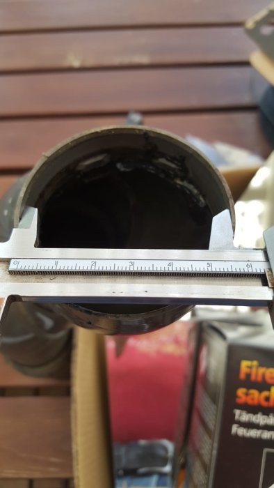 Mätning av avloppsrör med skjutmått visar innerdiameter ca 62 mm mot en röd bakgrund.