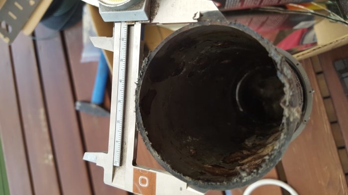 Skjutmått mäter inre diameter på ett svart avloppsrör, ungefär 62-63 mm, behov av standardidentifiering.