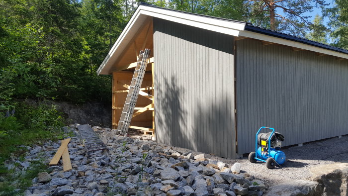 Nyuppsatt målad panel på framsidan av en byggnad med en stege och byggmaterial i förgrunden.