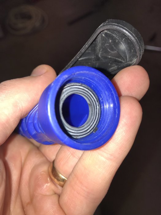Närbild på en blå ihoprullad vattenslangs inre gänga i en persons hand.