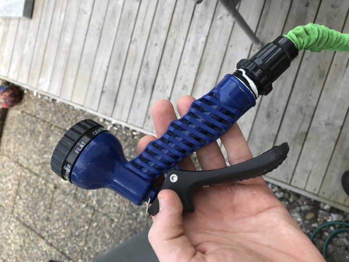 Hand som håller en blå vattenslang med munstycke som har en inre gänga.