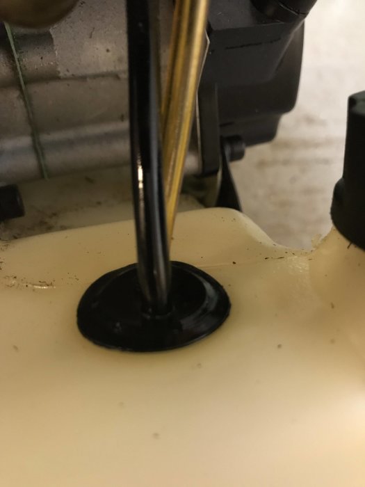 Bränsleslang genomföring med läckage på en bensintrimmers bensintank.