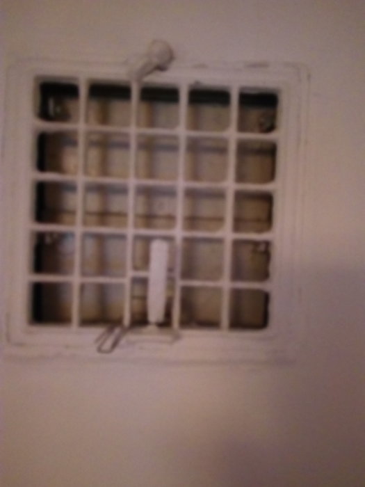 Ventilationsgaller med stängningsmekanism på en vägg som framstår som ohanterbar.