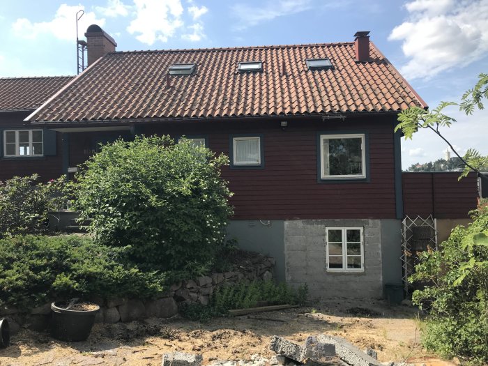 Tvåvåningshus under renovering, nederdelen delvis i betong, övervåning rödmålad, med takfönster.