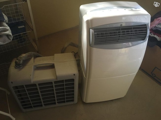 En inomhus- och en utomhusenhet av en split-aircondition placerade på ett golv bredvid en fönsterkarm.