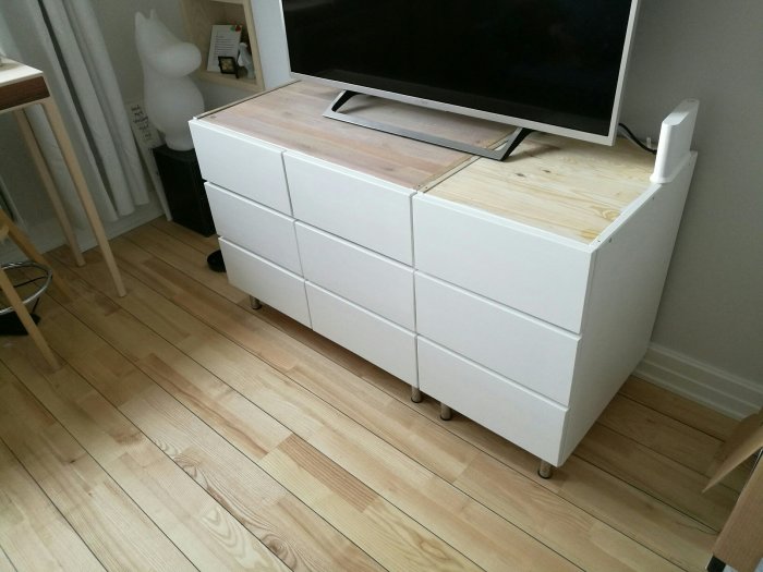 Bänkskiva av MDF och valnöt på vita hurtsar under en tv, med bearbetade hörn och laminatfinish.