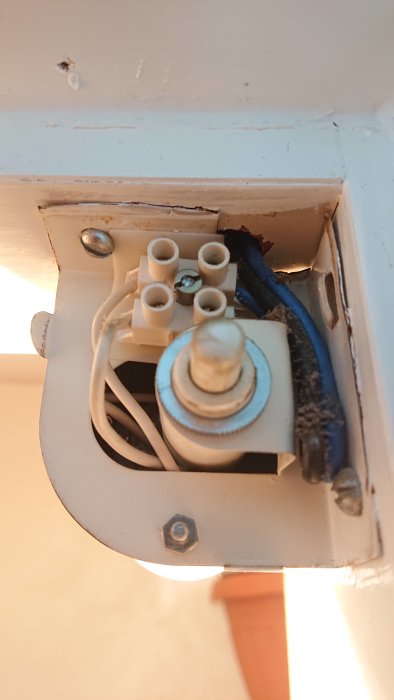 Elektrisk anslutning inne i en öppen lamparmatur med synliga kablar och anslutningsklemmar.