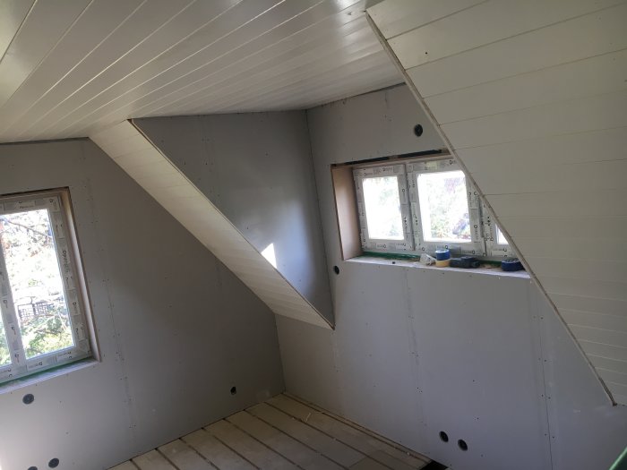 Delvis renoverat sovrum med ny panel och gipsväggar, samt smyg runt fönster under arbete.