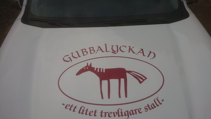 Reklamdekaler på bilflak med texten 'GUBBALYCKAN - ett lite trevligare stall' och en illustration av en häst.