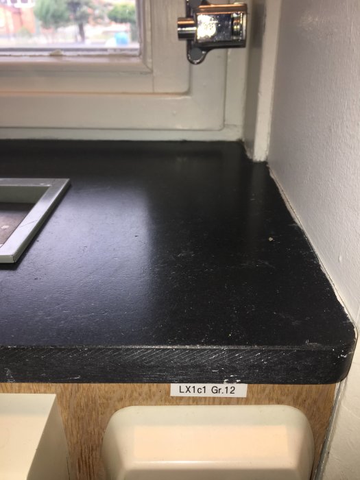 Fönsterbänk med svart skiva som visar olika mönster, diagonala snitt på övre delen och horisontella på nedre.
