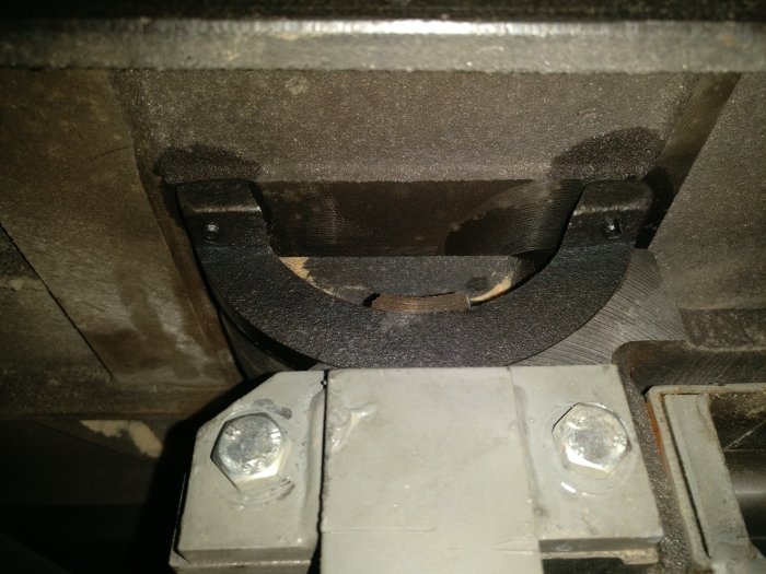 Närbild på en äldre bandsåg med fokus på sågblad, t-track och bultar.