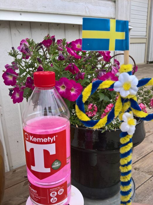 Midsommardekoration med svensk flagga, blommor och flaska med T-röd atopiskt lösningsmedel.