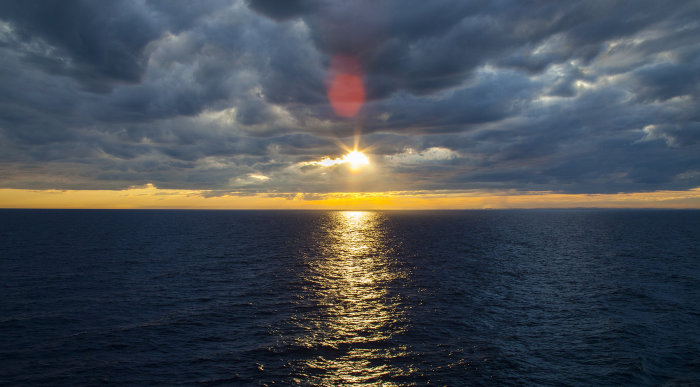 Solnedgång över havet med gul och blå himmel som påminner om svenska flaggans färger.