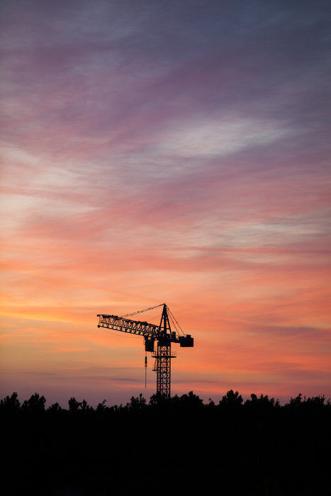 Solnedgång med orange och rosa himmel bakom silhuetten av en byggkran, skämtsam anspelning på svenska flaggan.