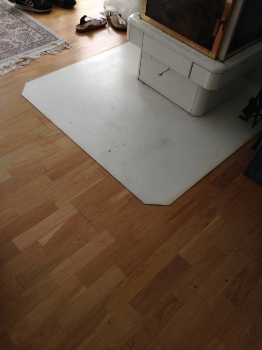 Gammalt trägolv med en vit kaminplatta, fråga om nivåutjämning vid ny golvläggning.