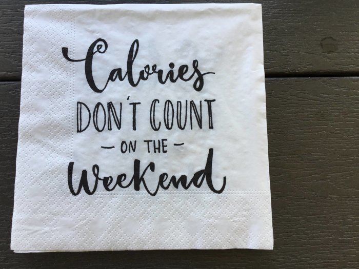 Servett med texten "Calories don't count on the weekend" på en träyta.