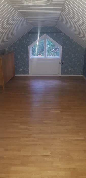 Övervåning med snedtak, tapetserade väggar och parkettgolv före renovering.