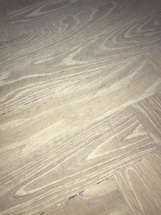 Slipat fiskbensparkettgolv i ek med synliga repor och matt yta efter oljebehandling.