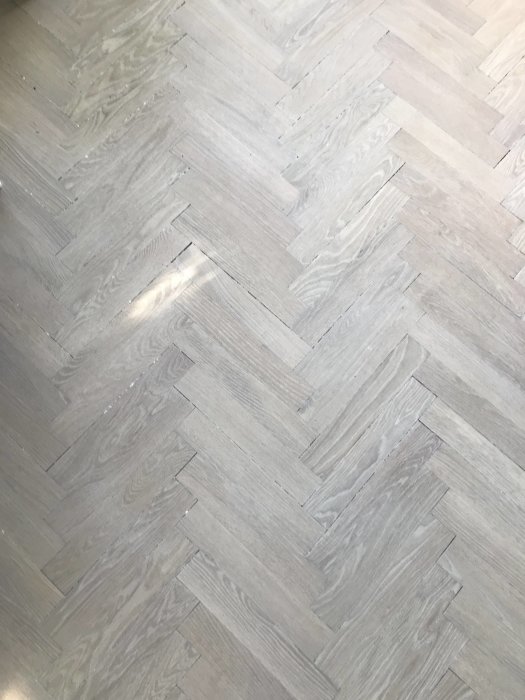 Slipat fiskbensparkettgolv i ek med matt yta och synliga repor efter renovering.