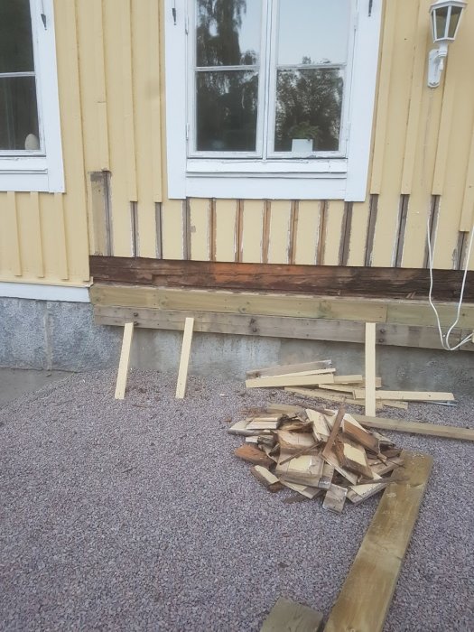 Renovering av fasad där nederkanten av fasadbrädorna är avskurna och ersatta med två nya brädor inför altanbygge.
